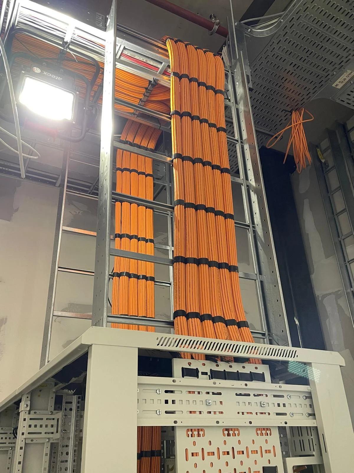 Geordende oranje databekabeling in kabelschacht